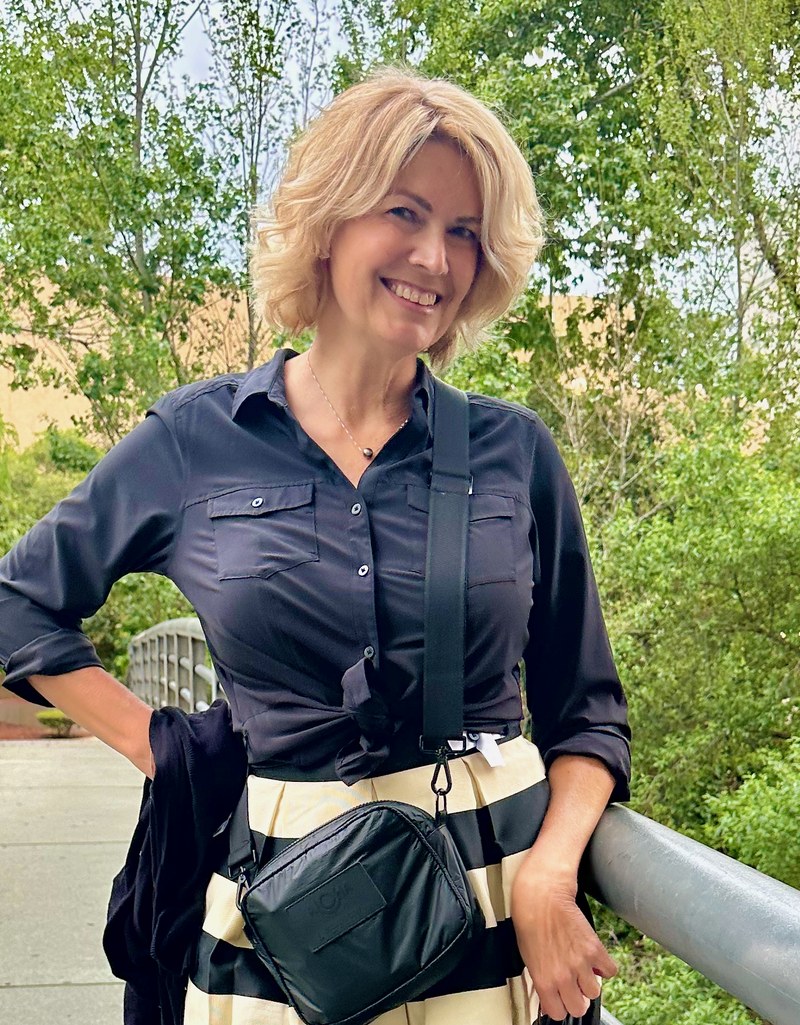 Michelle Tucker smiling on a footbridge, wearing a navy shirt and a black and cream striped skirt